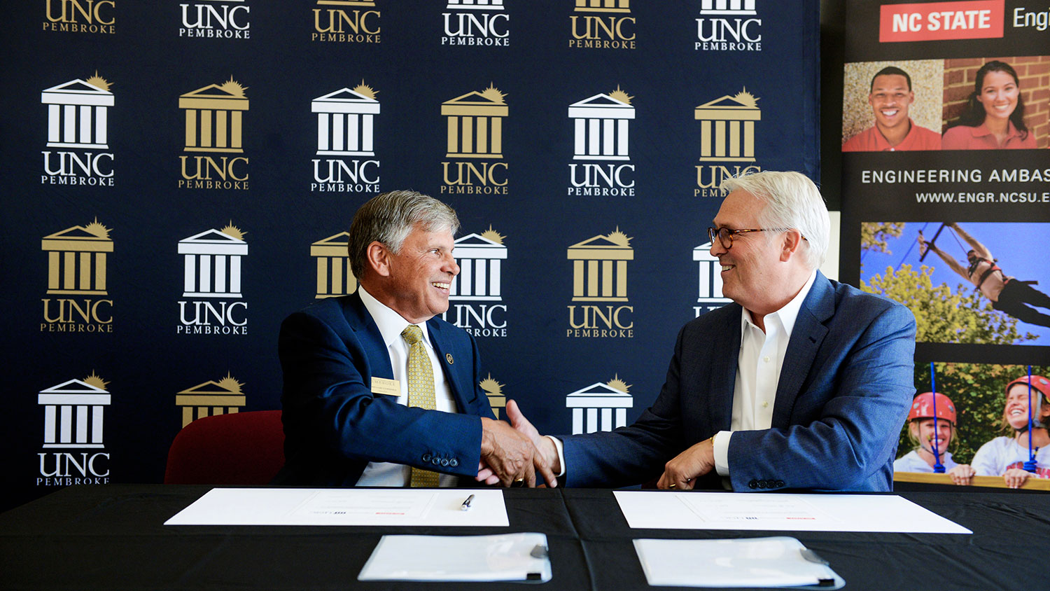 UNC Pembroke Chancellor Dr. Robin Gary Cummings, left, and NC State Chancellor Dr. Randy Woodson, right, shake hands after signing an agreement that creates a physics/engineering dual degree program between the two schools.
