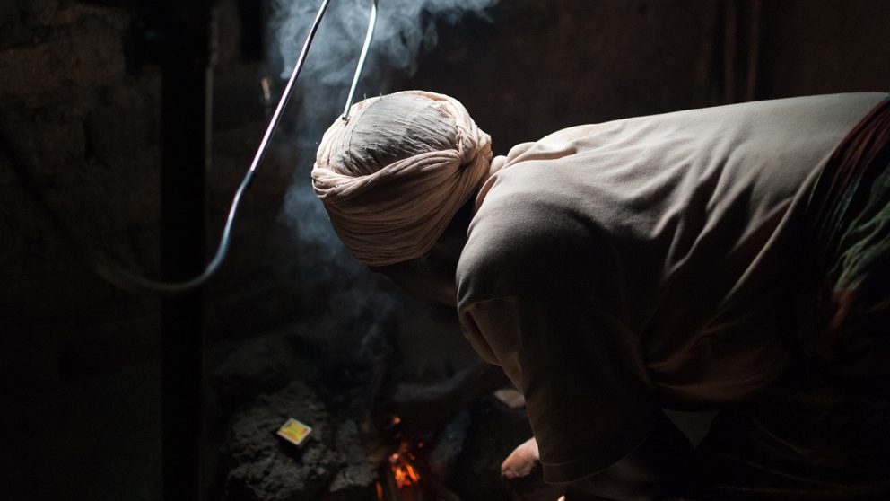 A woman in rural Rwanda tends a fire with a sampling probe above it during emission testing by the Grieshop Lab. (Photo: W. Champion)