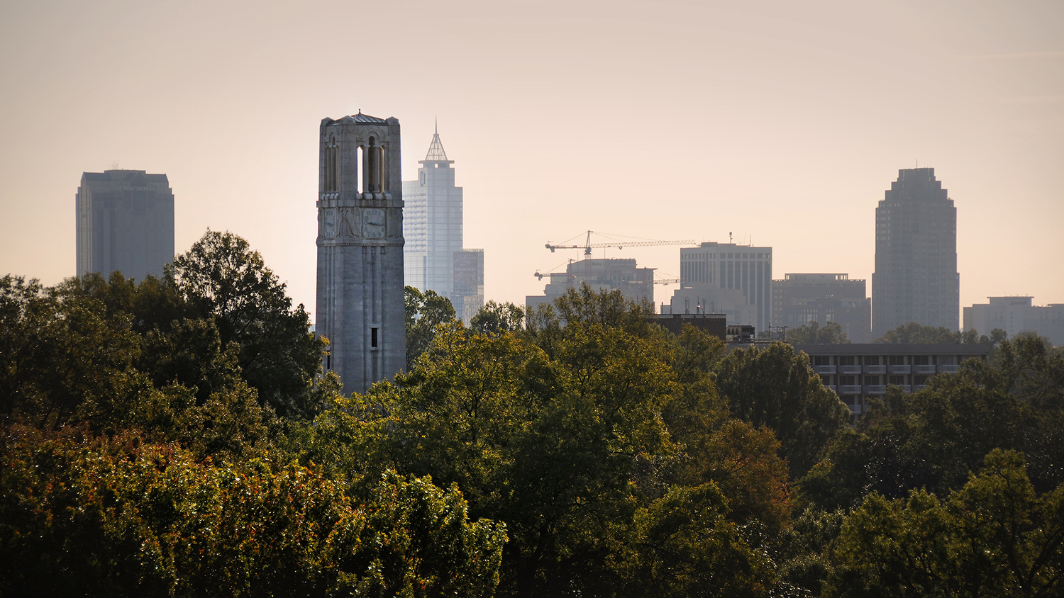 Downtown Raleigh skyline rises up behind the Memorial Belltower.
