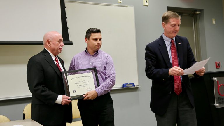Dr. Joseph DeCarolis, center, accepts an Outstanding Teacher Award from Dr. Louis Martin-Vega while Dr. Jerome Lavelle reads his citation.