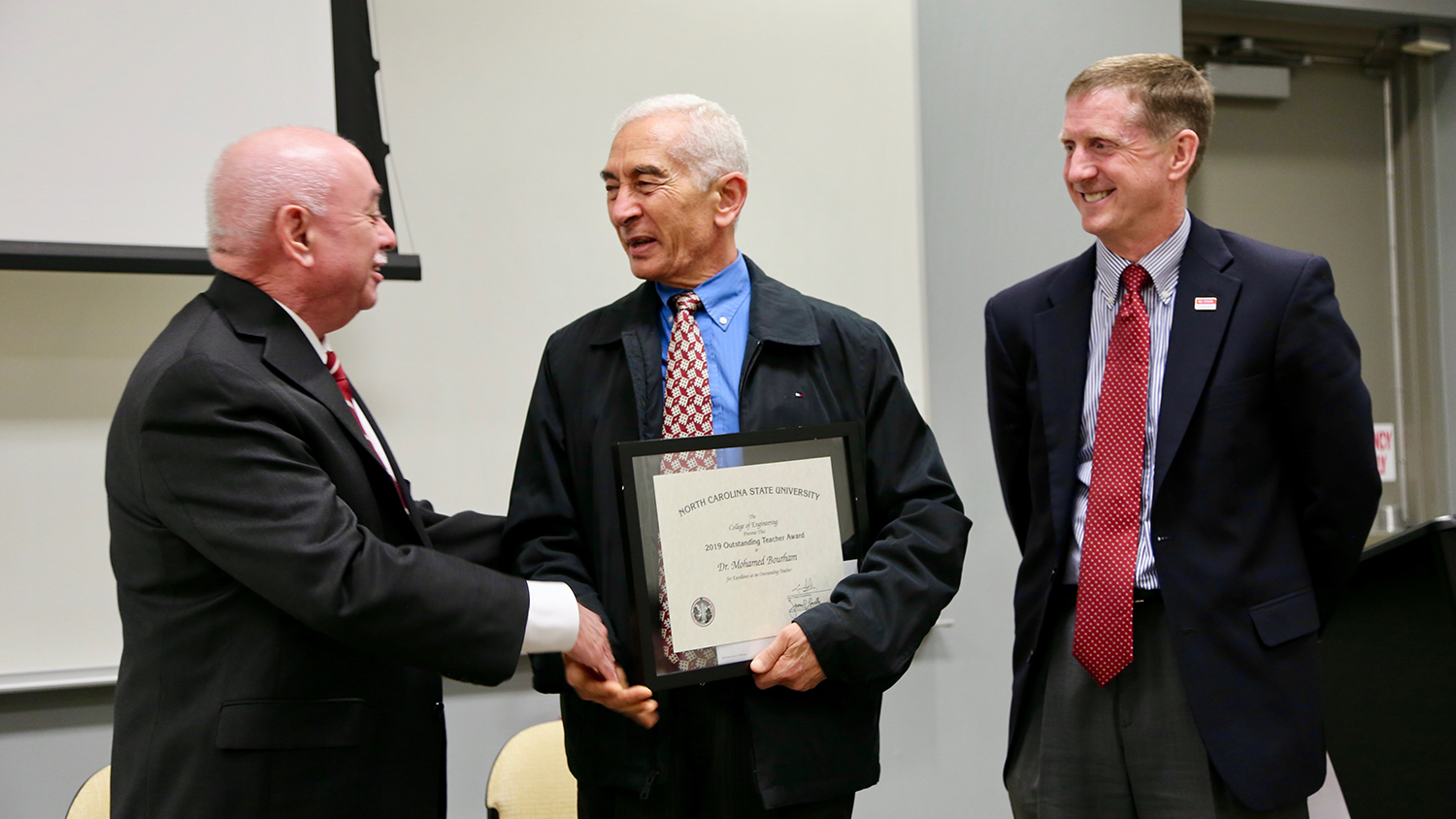 Dr. Mohamed Bourham, center, accepts an Outstanding Teacher Award from Dr. Louis Martin-Vega, left, and Dr. Jerome Lavelle.