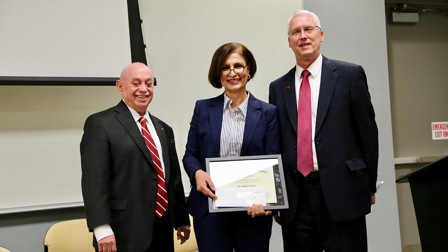 Dr. Afsaneh Rabiei, center, accepts Alcoa Foundation Distinguished Engineering Research Award from Dr. Louis Martin-Vega, left, and Dr. John Gilligan.