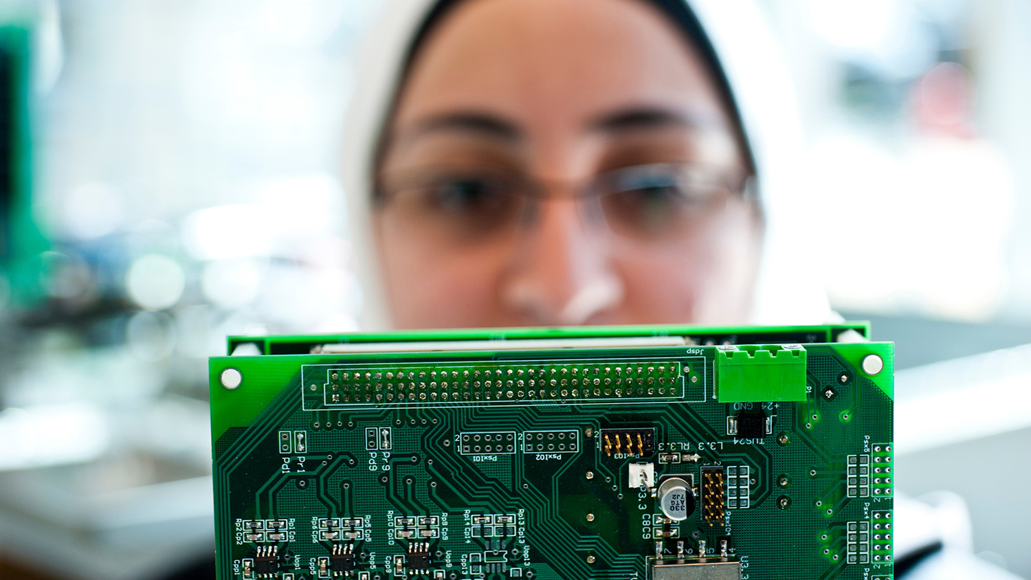 A woman holds a circuit board.