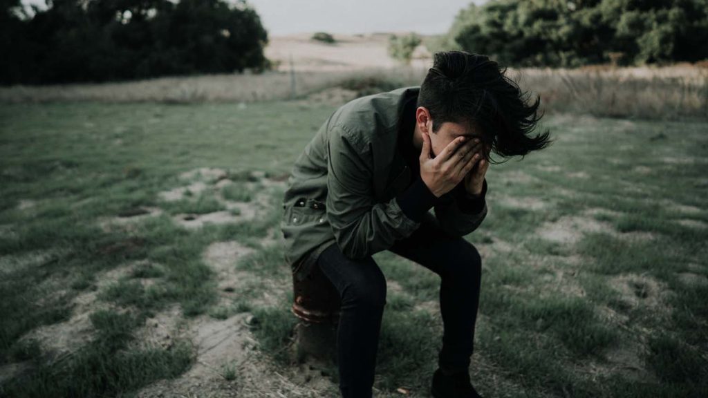person holds head in hands