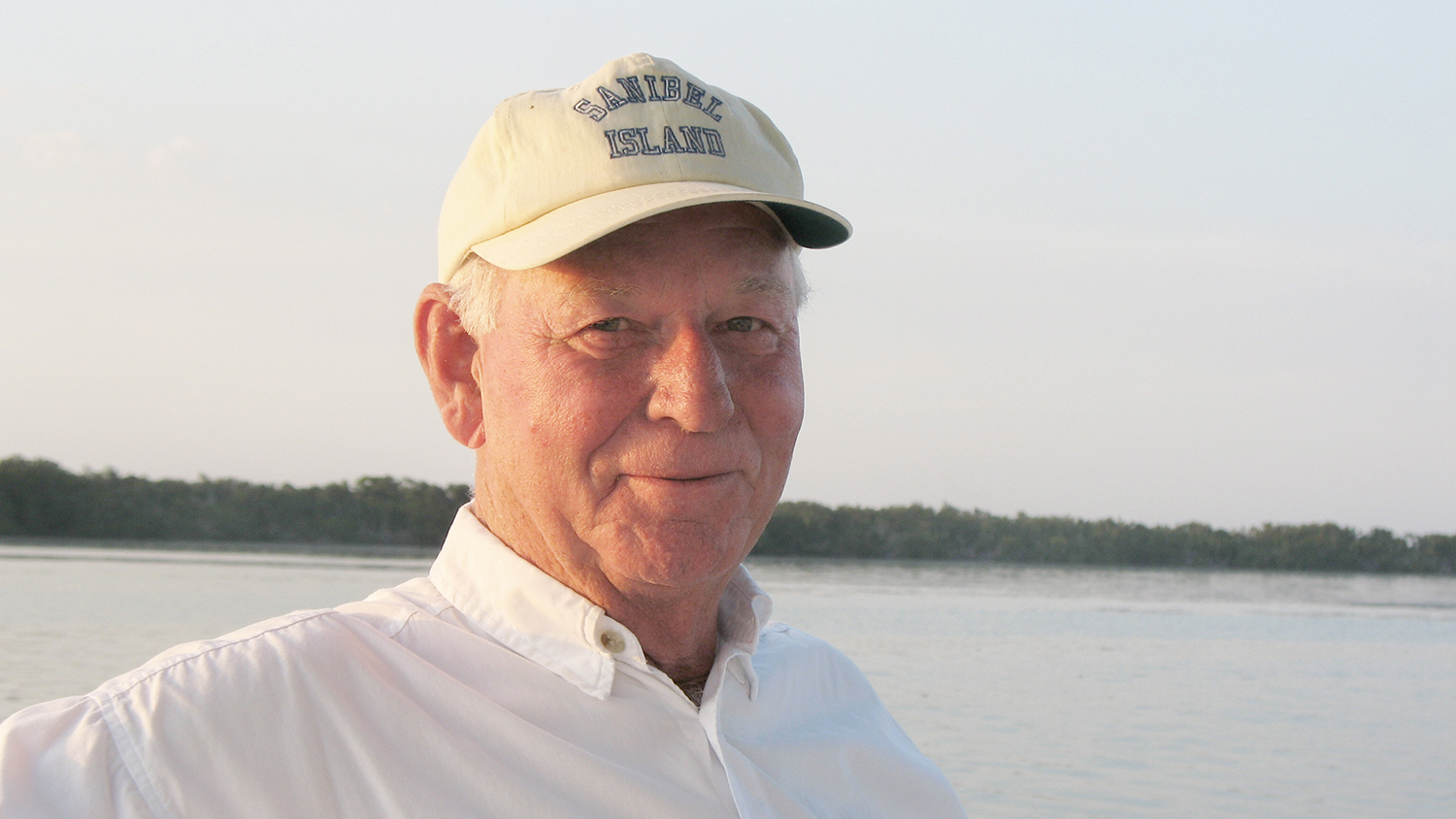 Jim Ellen in white shirt and baseball hat with a body of water behind him.