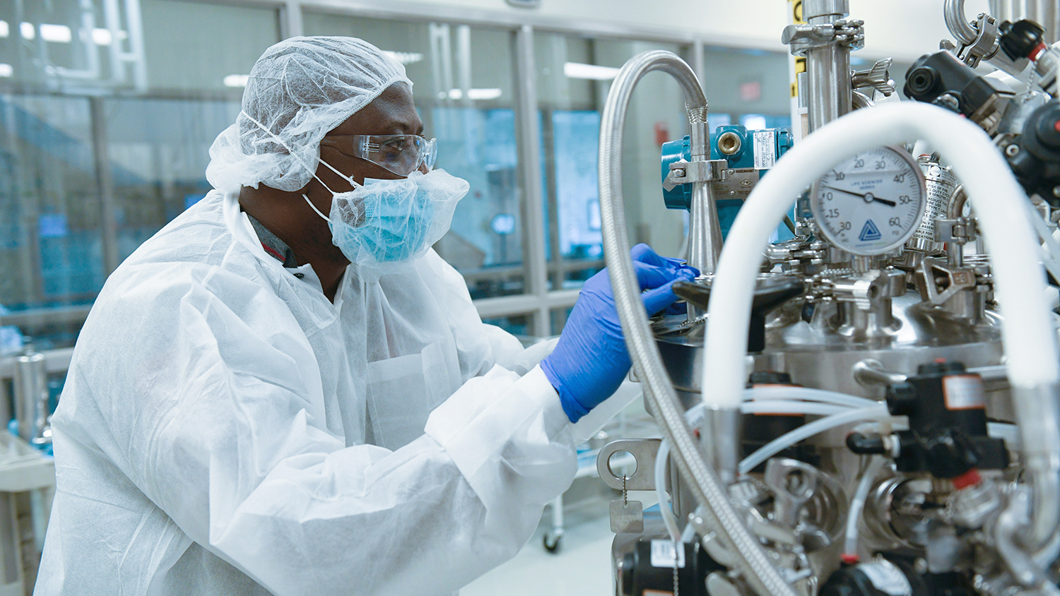 African American researcher dressed in full protective gear working in the lab.