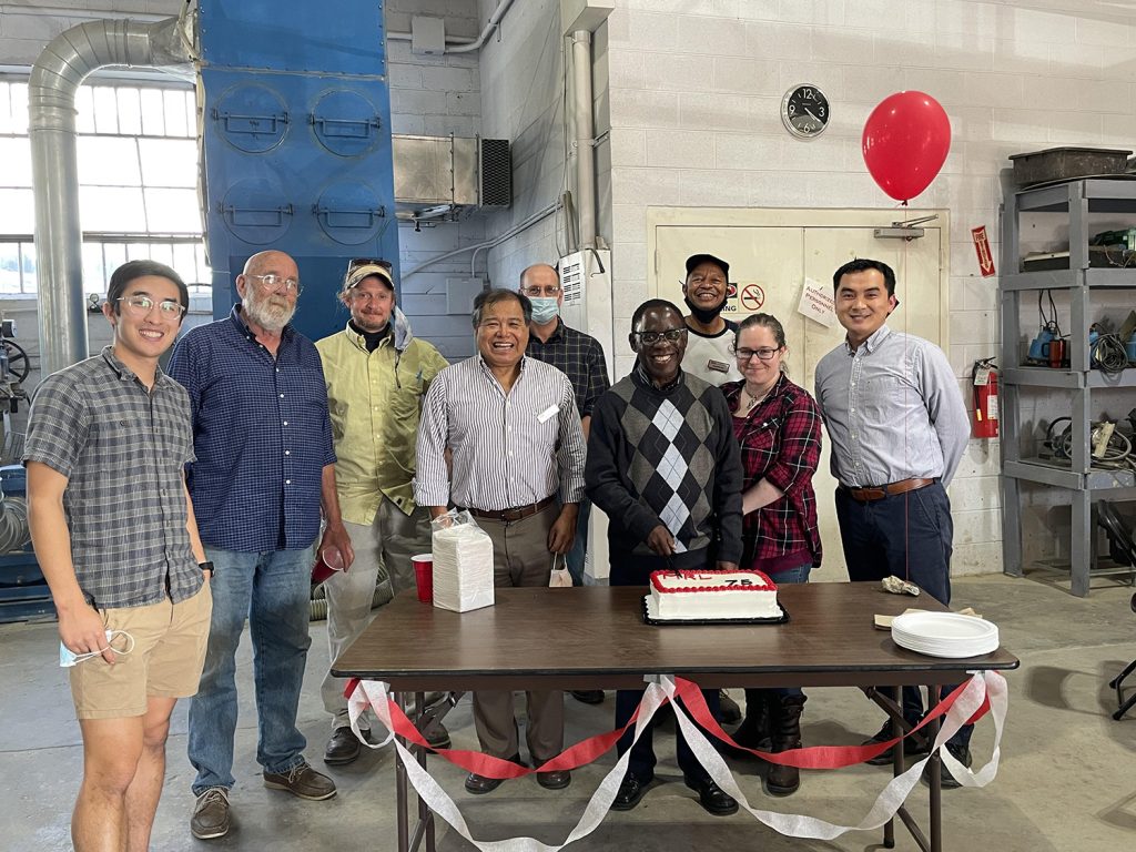 Minerals Research Lab staff standing in front of a table with cake and a balloon to celebrate the lab's 75th anniversary.