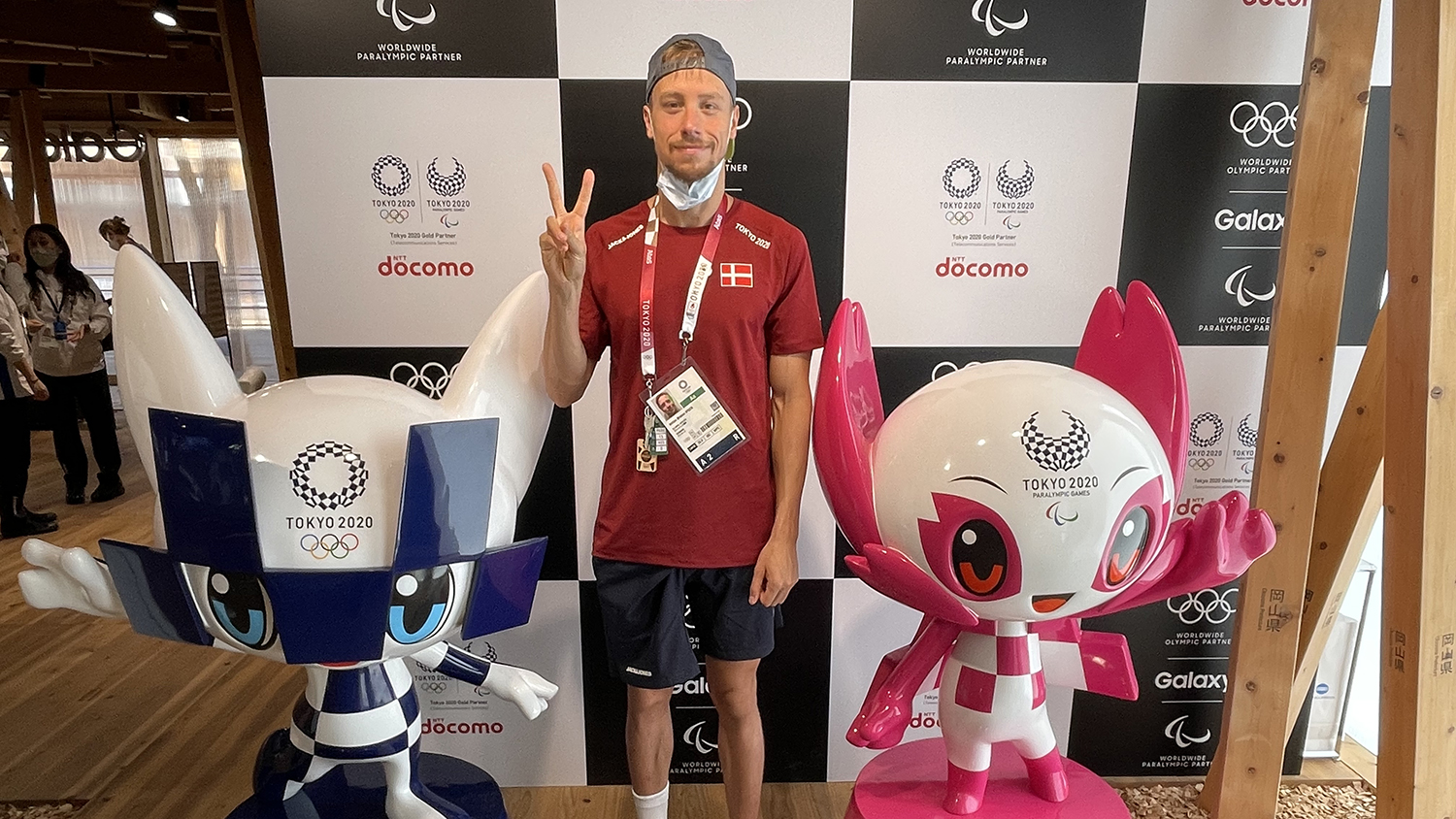 Anton Ipsen at the 2021 Olympic Games standing in behind two cartoon figures.