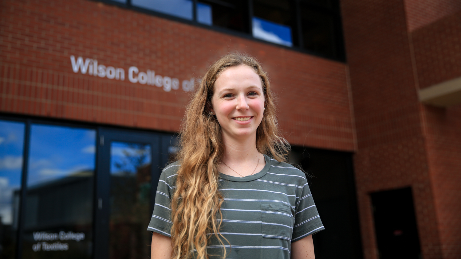 Shannon Sefton standing outside the entrance to Wilson College of Textiles.