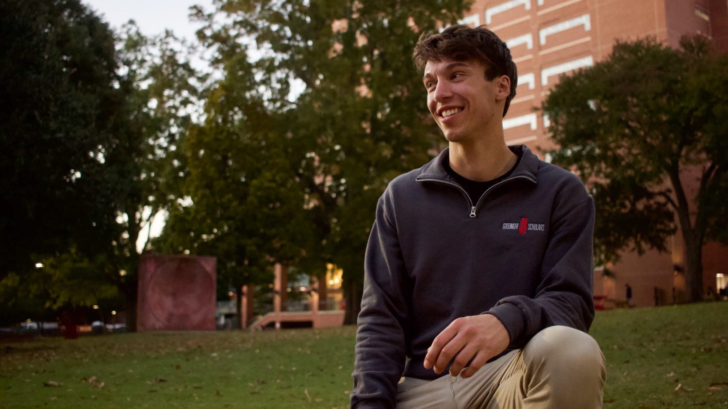 Jonathan Moore sitting outside with tree and building in the background.