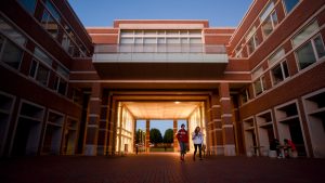 Students walking underneath atrium of Engineering Building I at dusk.