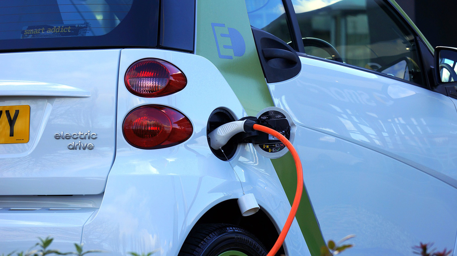 Side view of white electric car recharging.