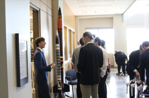 Students discussing design project next to model rocket display.