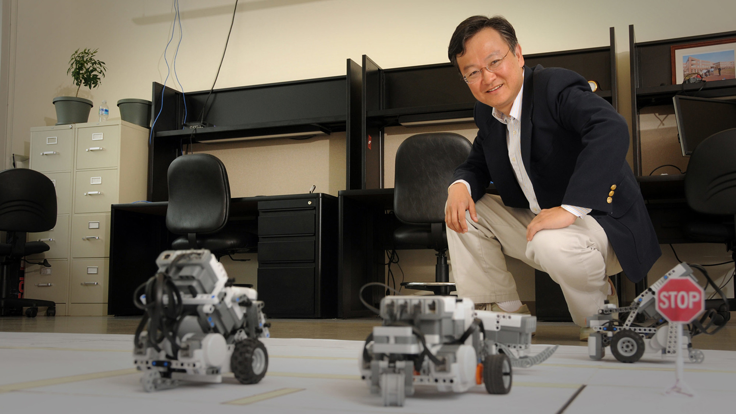 Dr. Chow poses next to devices in lab.