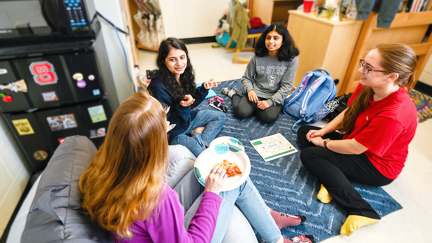 Group of young female students sitting in a circle while conversing.