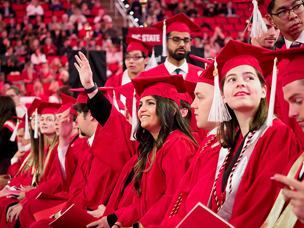 Students dressed in red caps and gowns participate in Fall 2019 graduation at the PNC Arena.