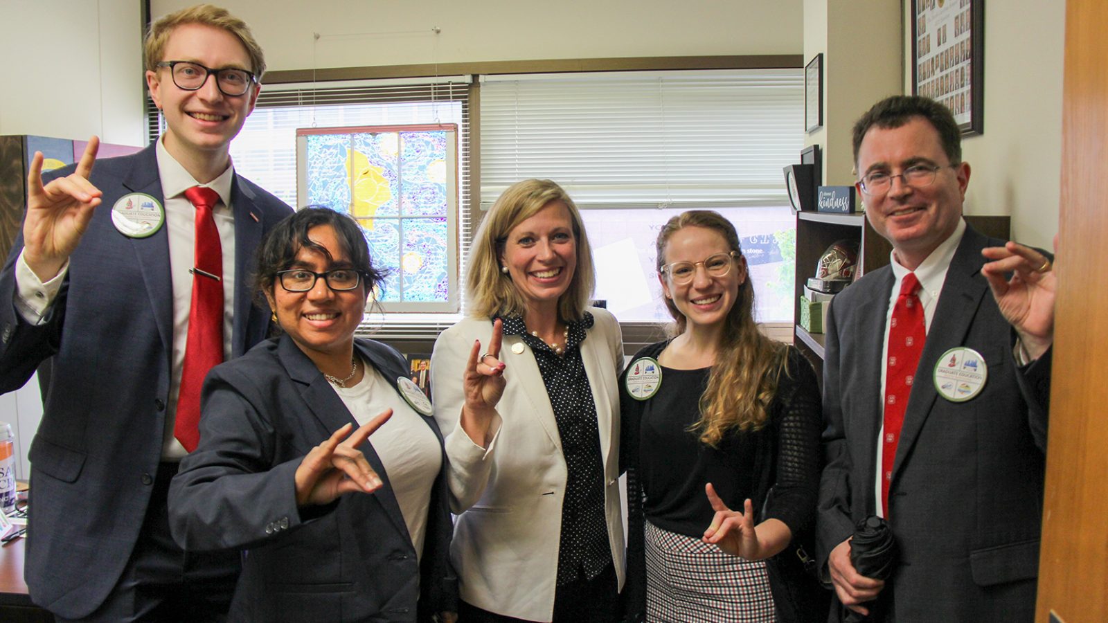 Adam Schmidt, left, and fellow students flash the NC State University wolf sign.