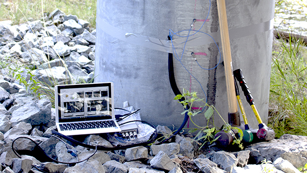 Laptop and several handtools next to a concrete piling ready for testing.