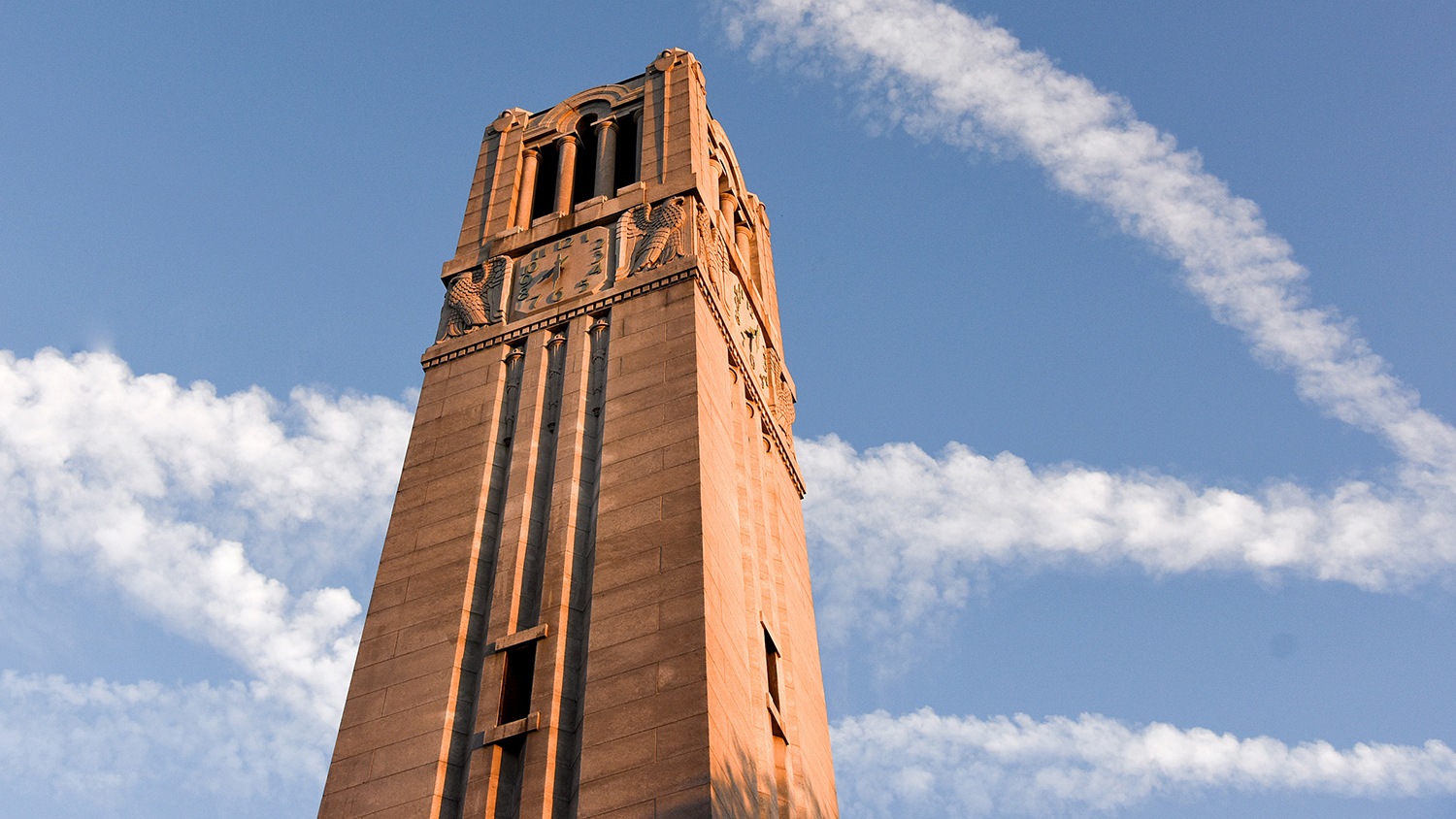 The NC State Memorial Belltower lit by late evening sunlight.