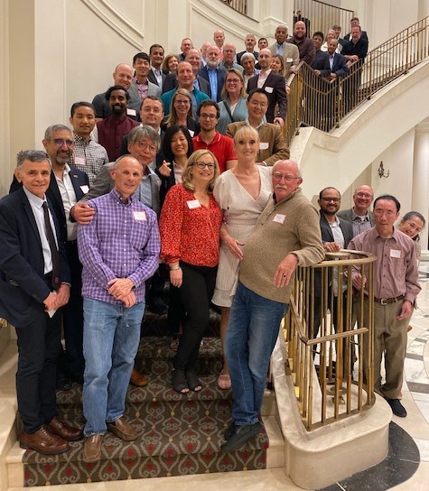 Associates and colleagues gather for a group photo on curving stairs during J. Michael Doster's retirement celebration.