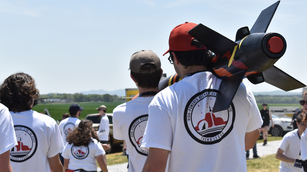 Members of the MAE rocketry team carry their model rocket to the launch site.