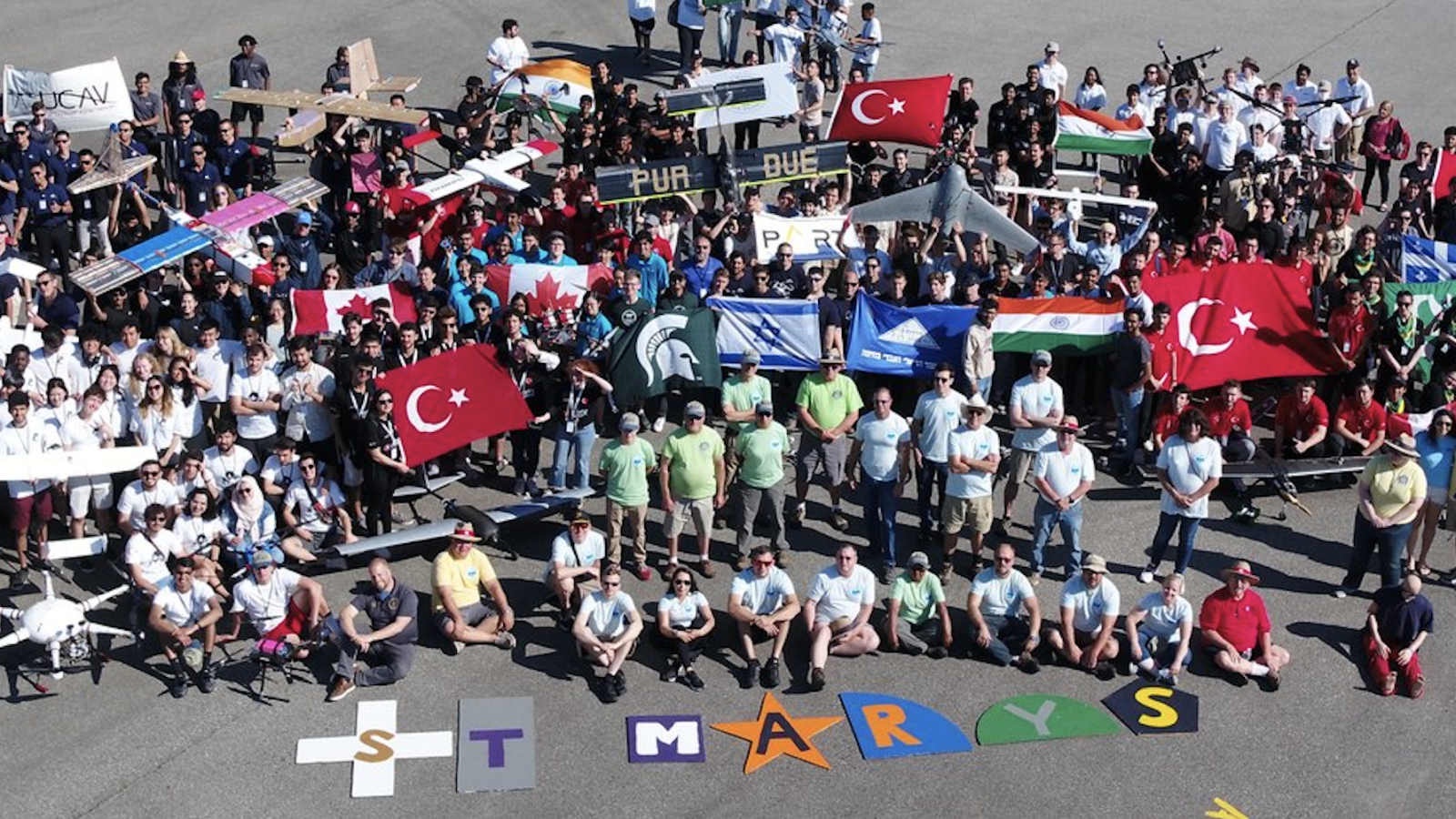 Teams representing a variety of nations pose for a group photo taken from above.