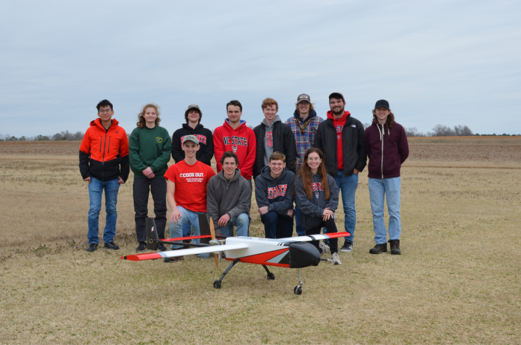 The NC State College of Engineering MAW Aerial Robotics Club 2022 team poses for a group photo while standing behind their aerial drone.