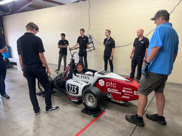 The NC State Formula SAE team surrounds car while prepping it for competition.