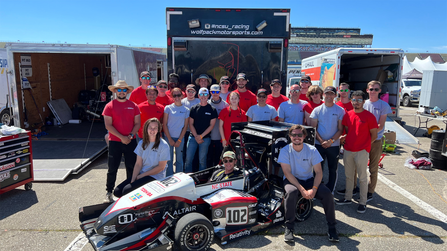 NC State College of Engineering Formula SAE team poses for a group picture around their race car.