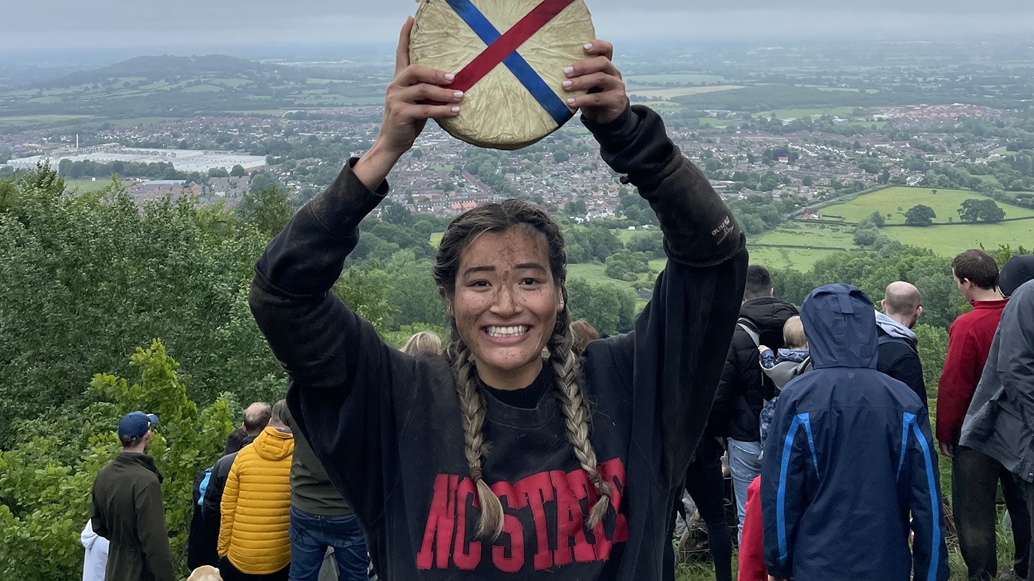 Abby Lampe holds aloft her winning cheese wheel at the 2022 Cooper's Hill Cheese-Rolling and Wake near Gloucester, England.