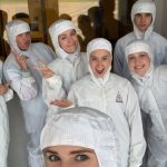 Group of summer camp participants dressed in heat-to-toe white lab clothing pose for a light-hearted group photo.