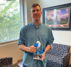 Chris Vermillion holds his Edge Award, a blue and white trophy in the shape of a wave.