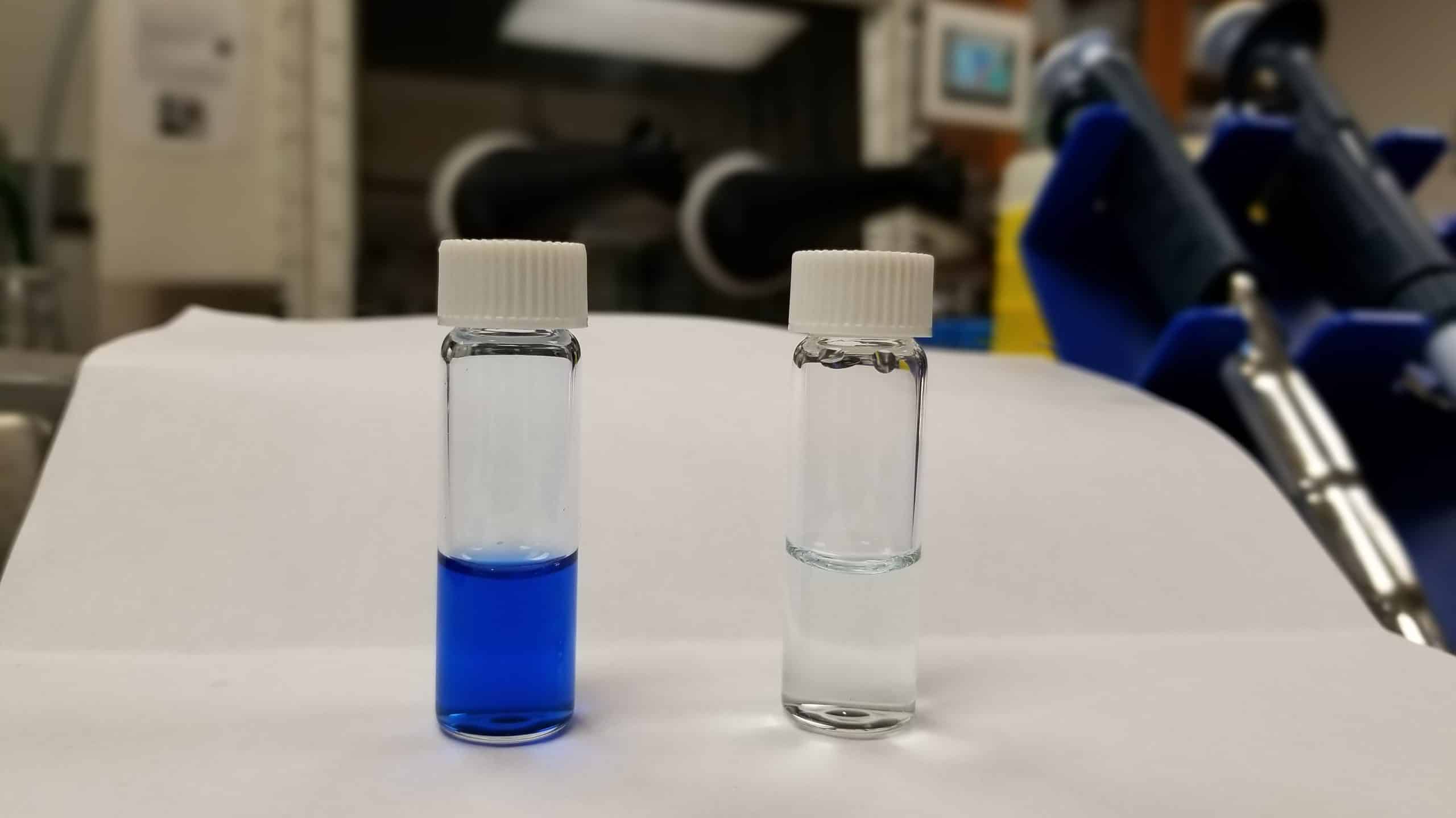 Two vials of water. One on left is colored blue, the one on the right is clear.