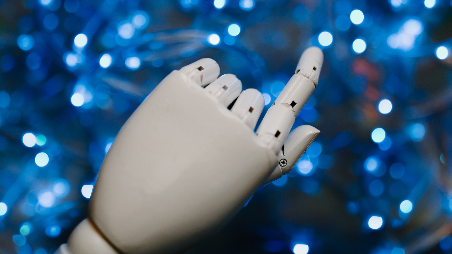 Glossy white plastic robotic hand with index finger extended over a white and blue illuminated background.