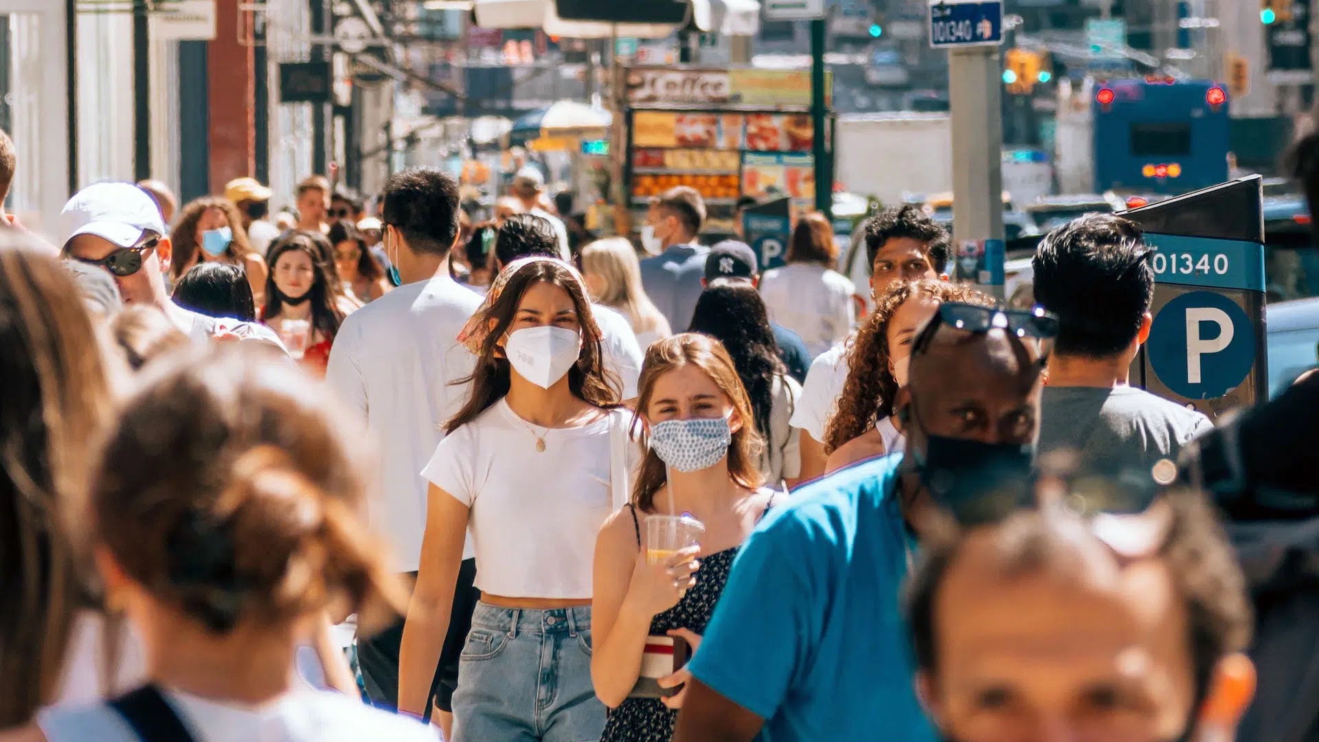 Exterior photo of pedestrians with focus on several wearing face masks.