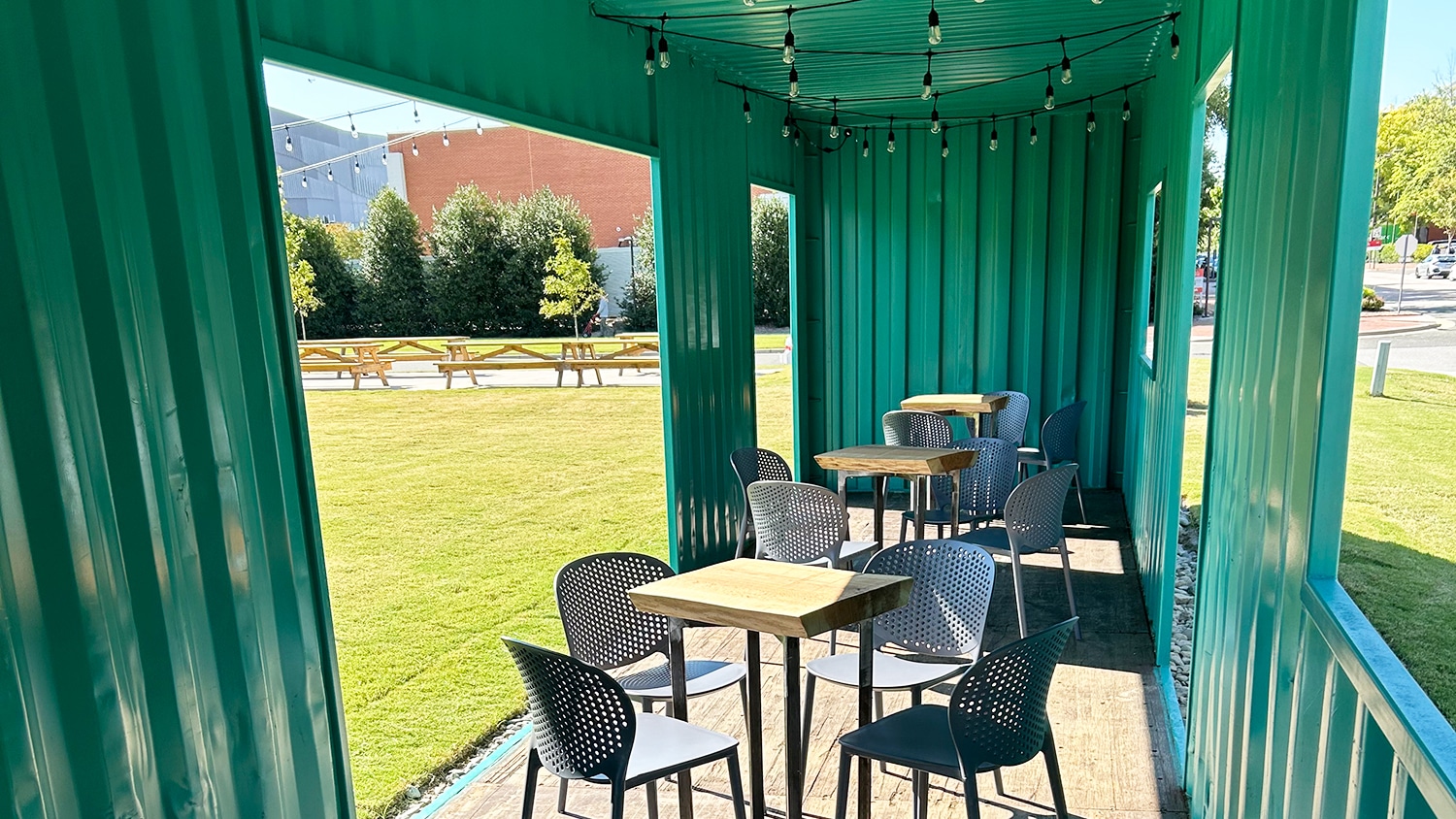 Interior photo of green shipping container repurposed as a social gathering spot complete with chairs and tables.