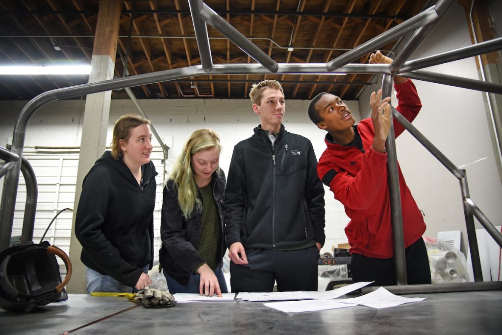 Mechanical engineering's Bryon Spells (right) points out recent welding work to SolarPack teammates while checking on the progress of their car at Eastern Rod and Customs.
