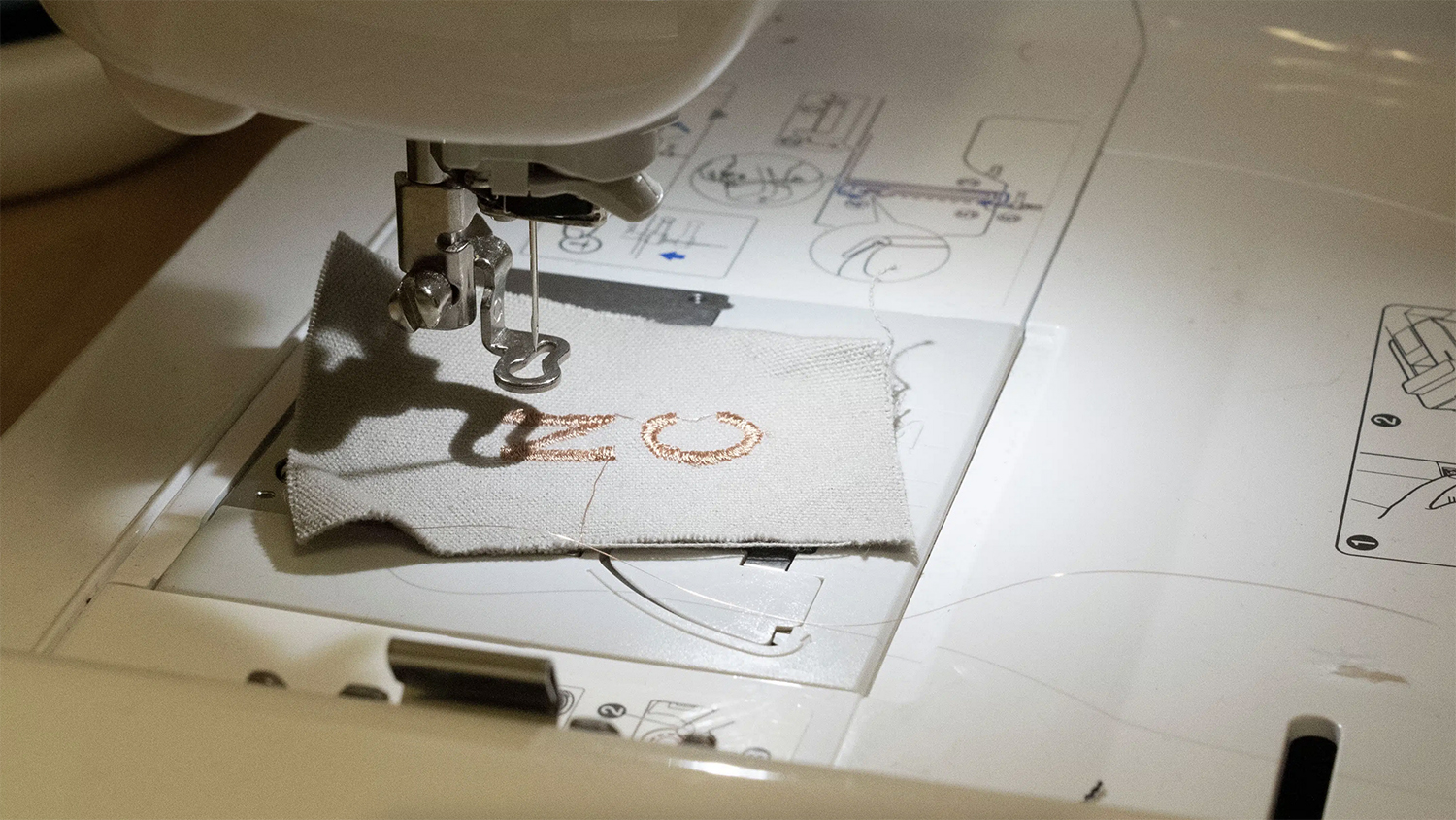 Closeup of embroidery work beneath spotlight and sewing machine.