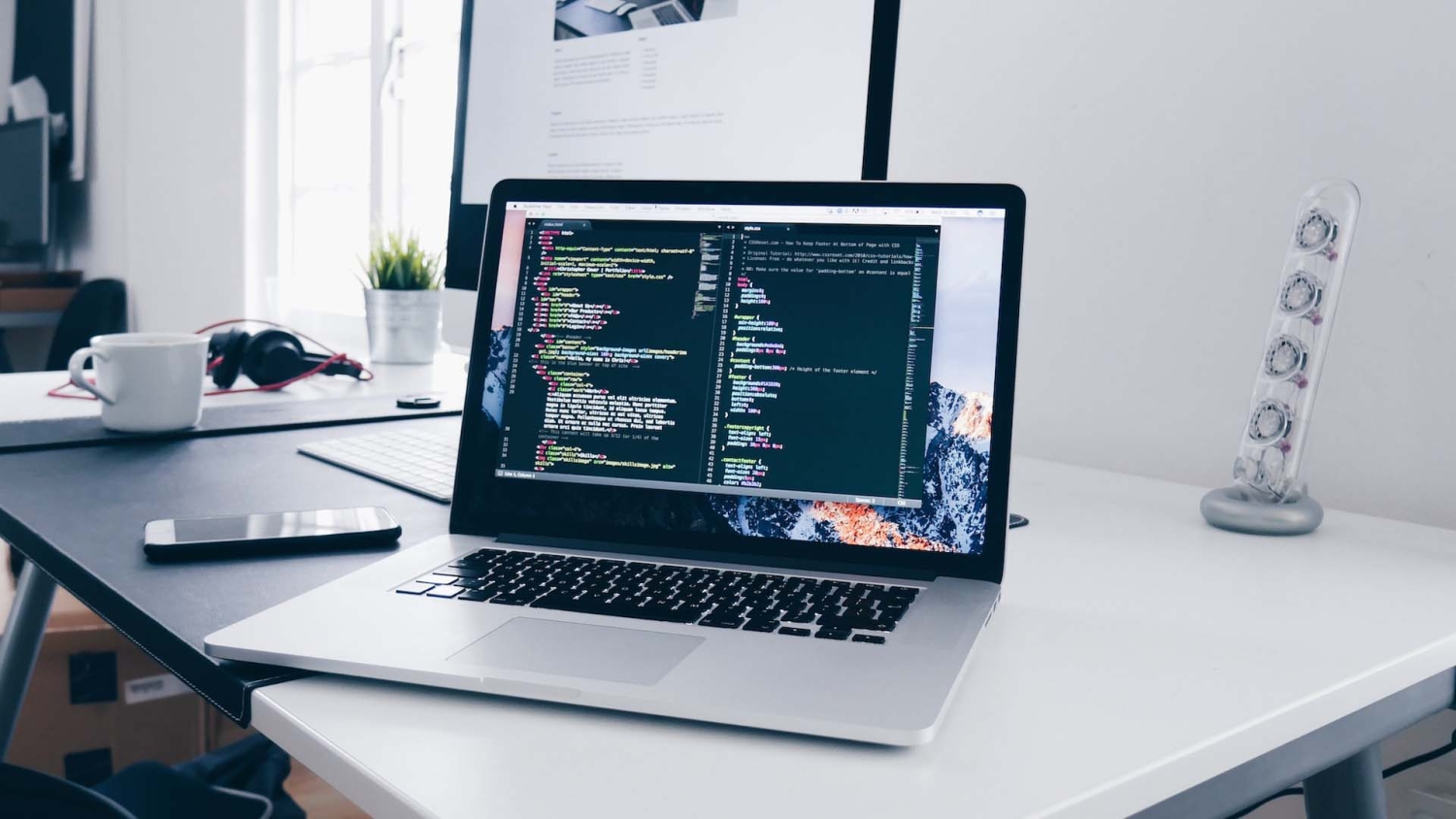 a laptop on a desk is open. the screen shows streaming code.