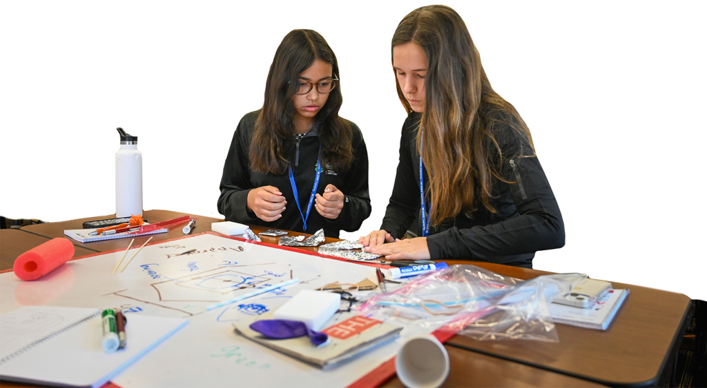 Two female summer camp participants work on a project together.