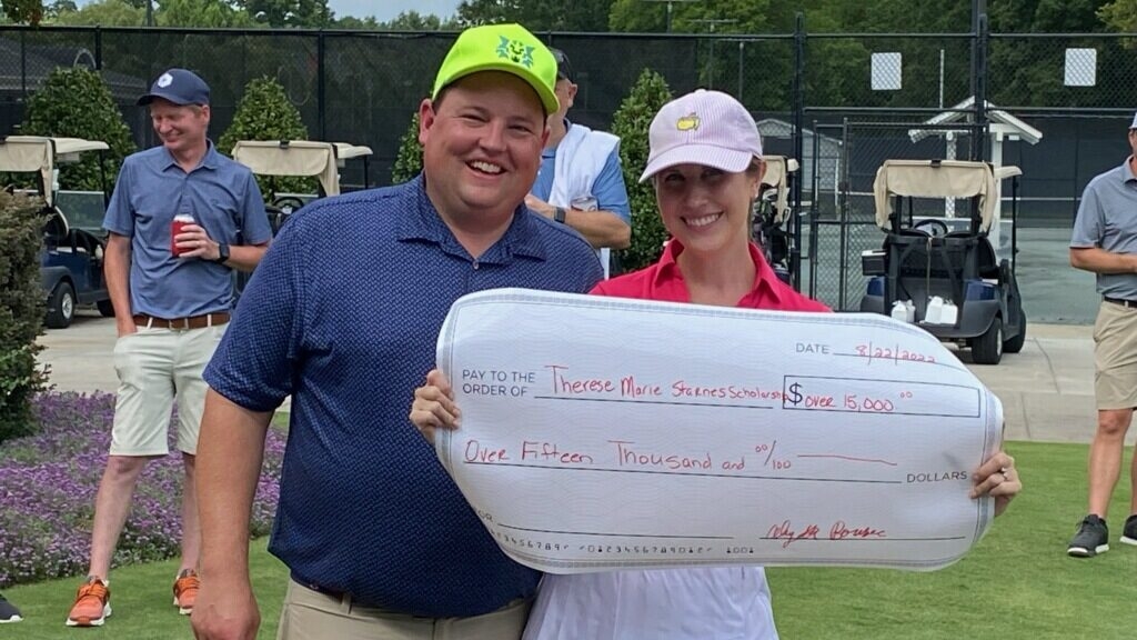 Kyle and Alyssa holding a presentation check at their golf tournament