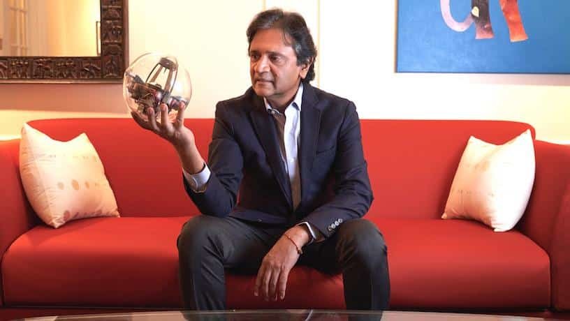 Shree Nayar sitting on a red couch holding a clear sphere.