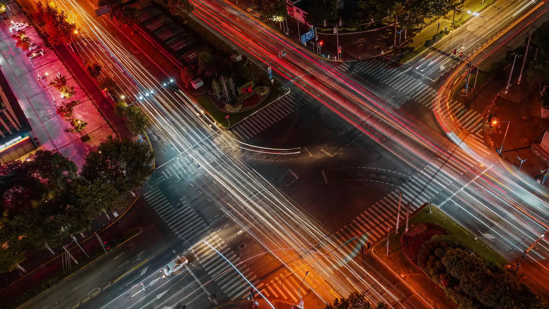 Nighttime aerial time-lapse view of city intersection and headlights of traffic.