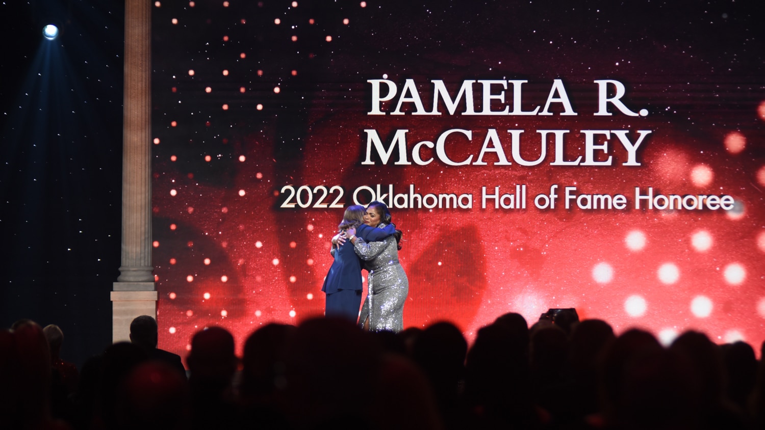 Pamela McCauley hugs presenter at Hall of Fame awards ceremony.
