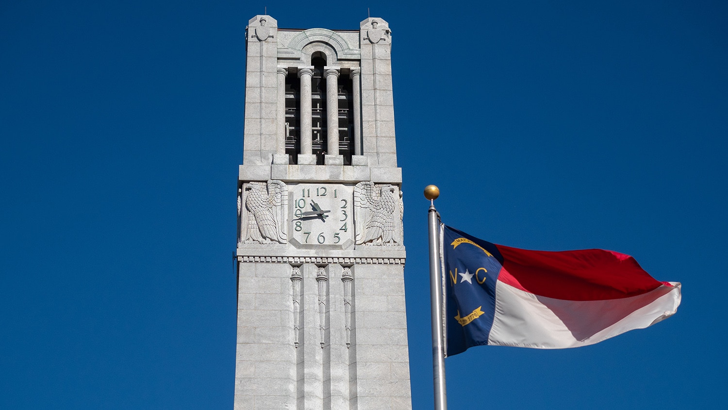 The state flag flies in front of the NC State Memorial Belltower on a fall morning.