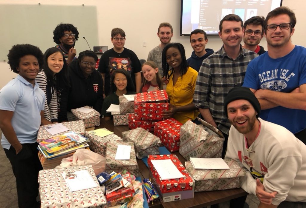 Acts2Fellowship, or A2F, pause wrapping gifts to pose for a group photo.