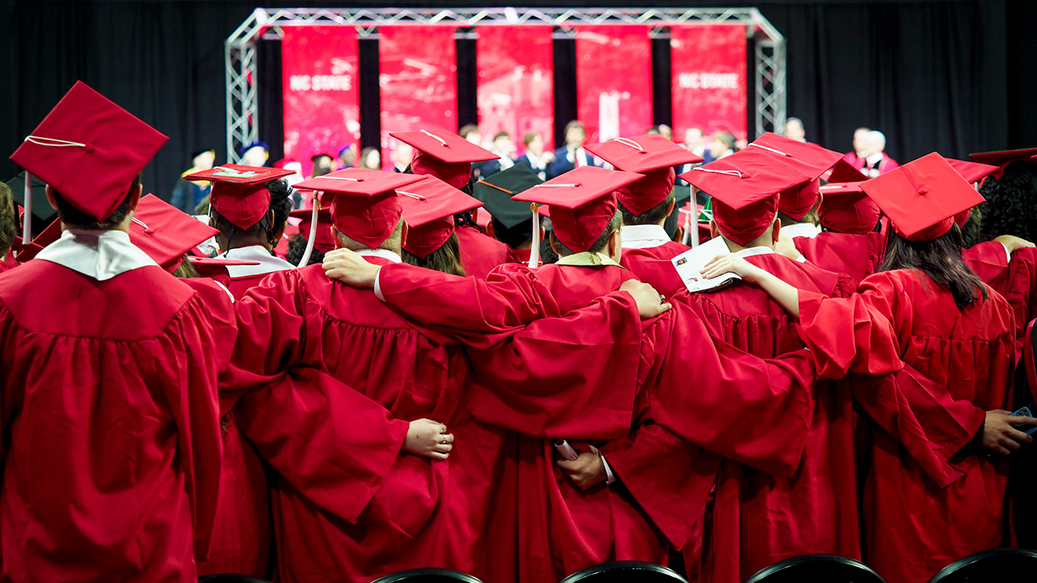 Students celebrate their fall 2022 graduation during commencement exercises on December 17 at PNC Arena. All are dressed in NC State red caps and gowns.