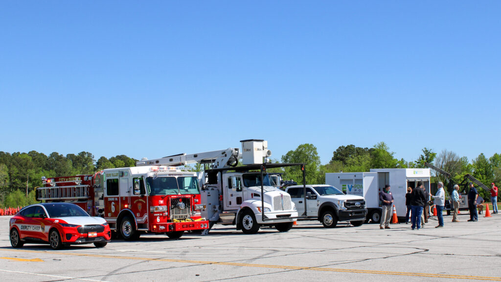 A row of alternative fuel vehicles sitting in a row. A passenger sedan, a firetruck, a utility truck and pickup truck.
