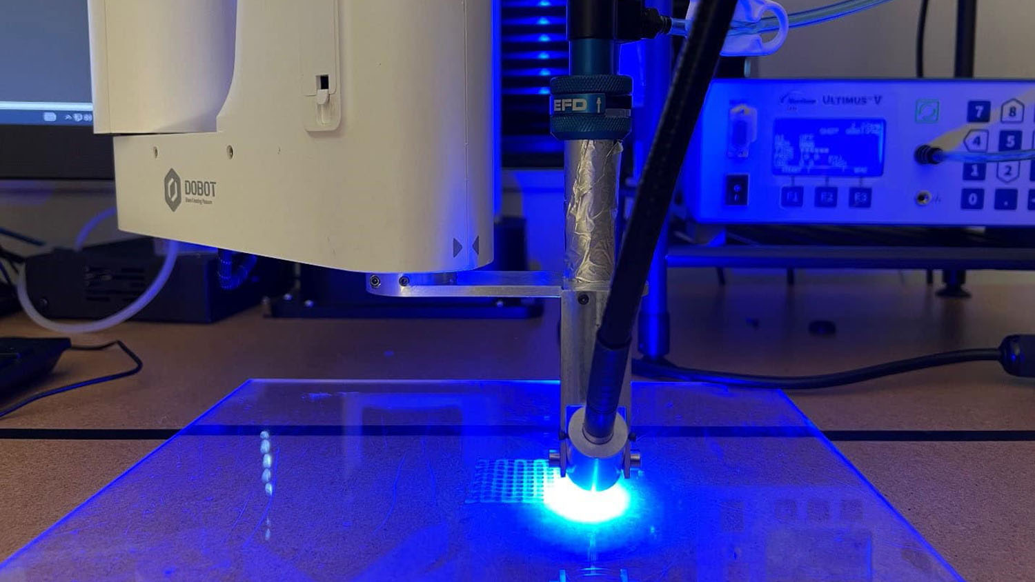 Surrounded in a blue glow with a white light at center, a 3D printer is in the process of producing a carbon dioxide filter.