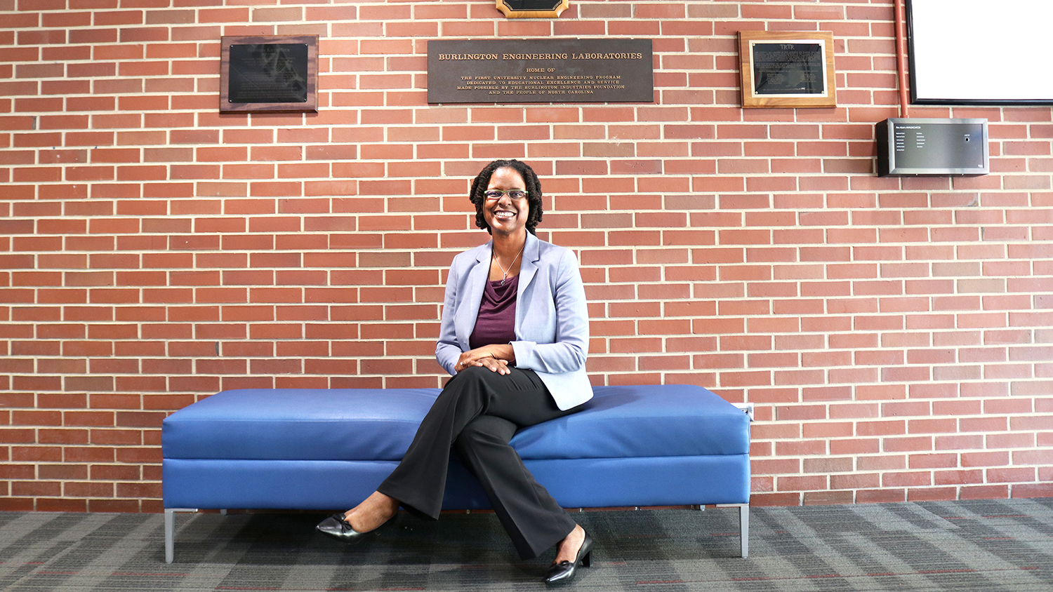 Lisa Marshall sitting on a blue couch in the Burlington Engineering Laboratory lobby.
